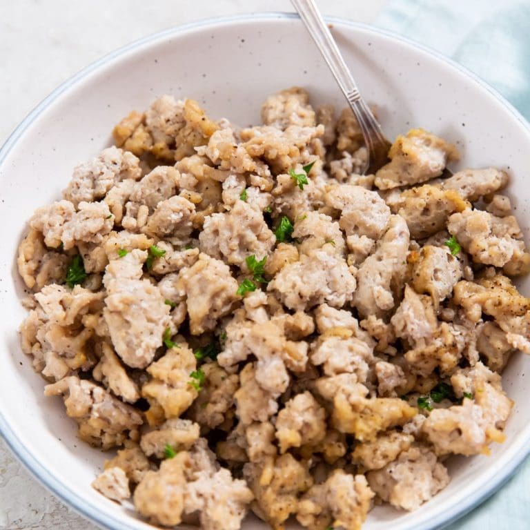 white bowl with chicken inside it.. blue towel and parsley in the back