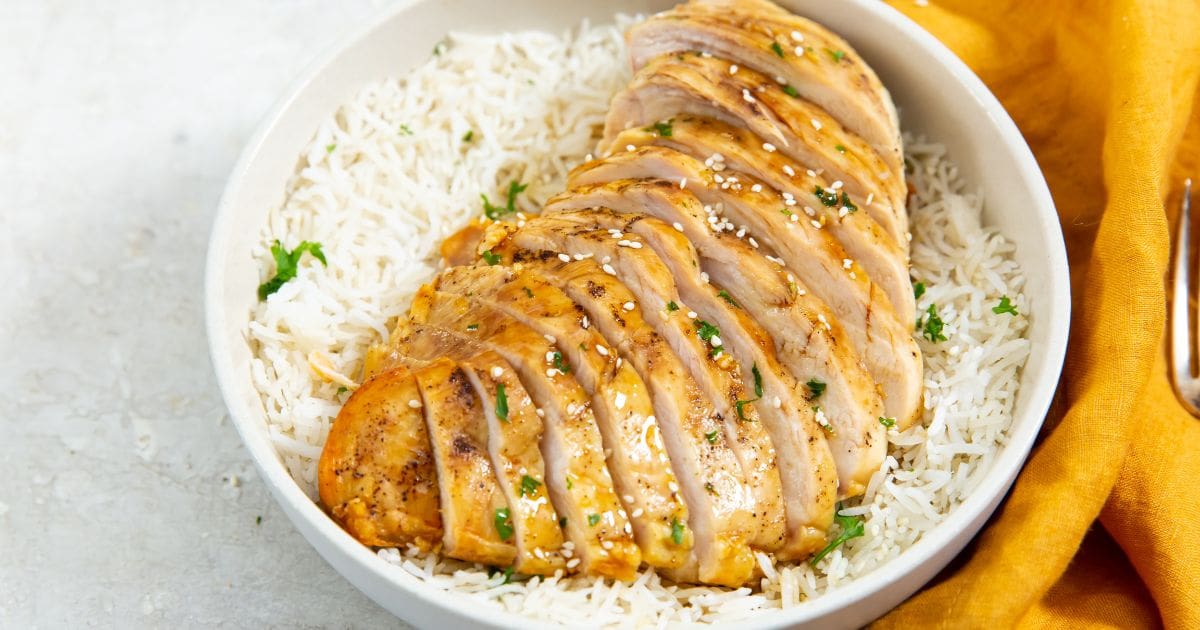 chicken on top of a bed of rice. parsley sprinkled on top. orange towel next to it.