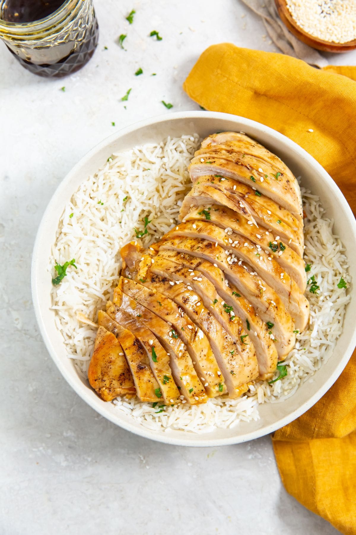 chicken on top of a bed of rice. parsley sprinkled on top. orange towel next to it.