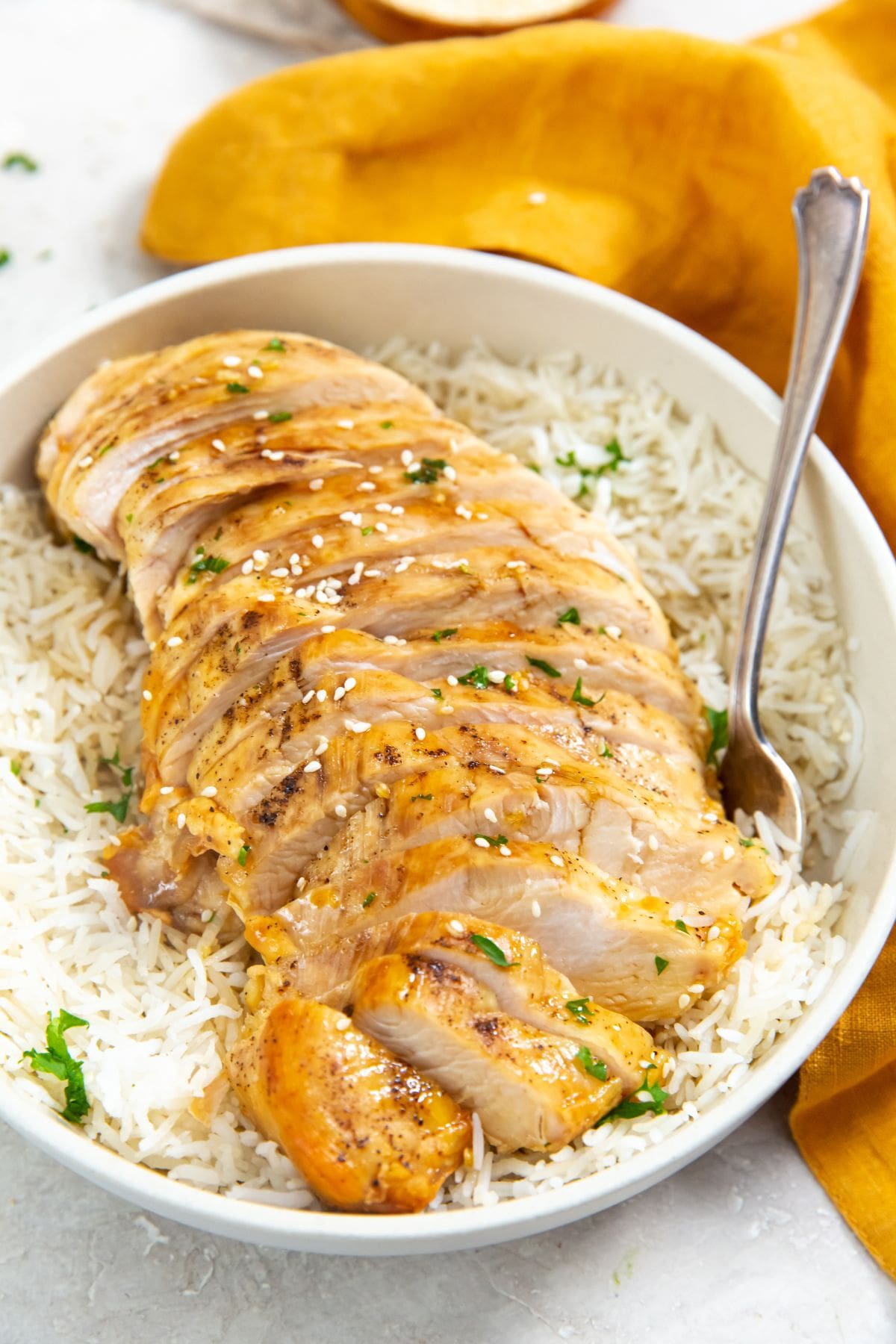 chicken on top of a bed of rice. parsley sprinkled on top. orange towel next to it.