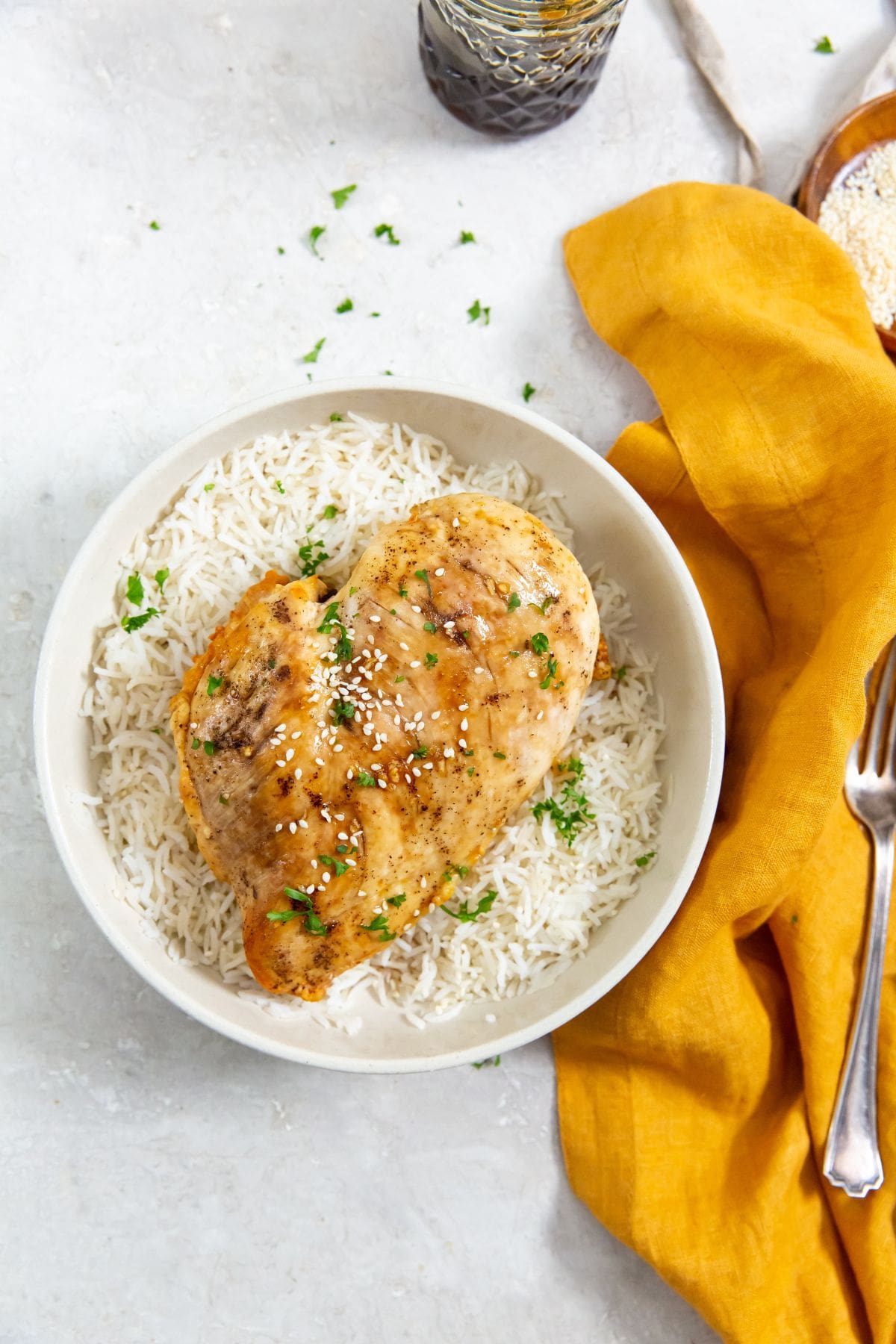 chicken on top of a bed of rice. parsley sprinkled on top. orange towel next to it.