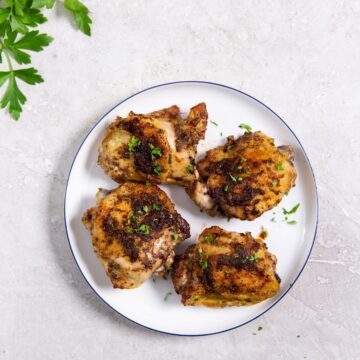 white plate with chicken on it parsley in the back