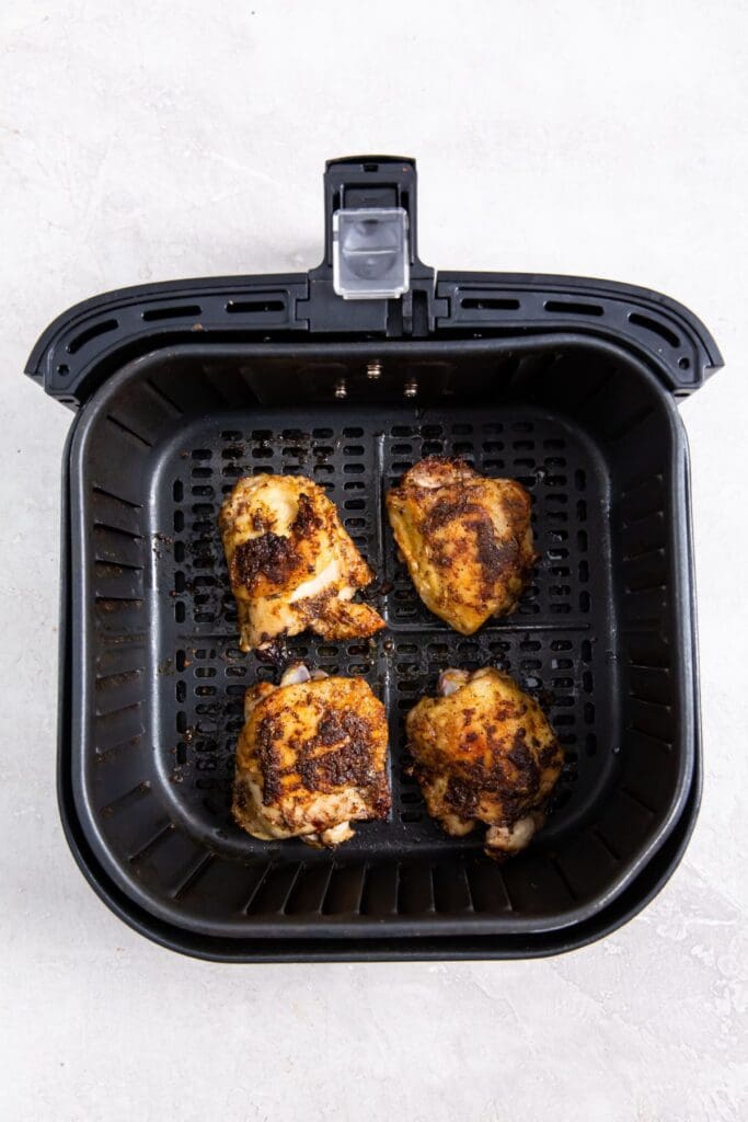 black air fryer basket with cooked chicken inside