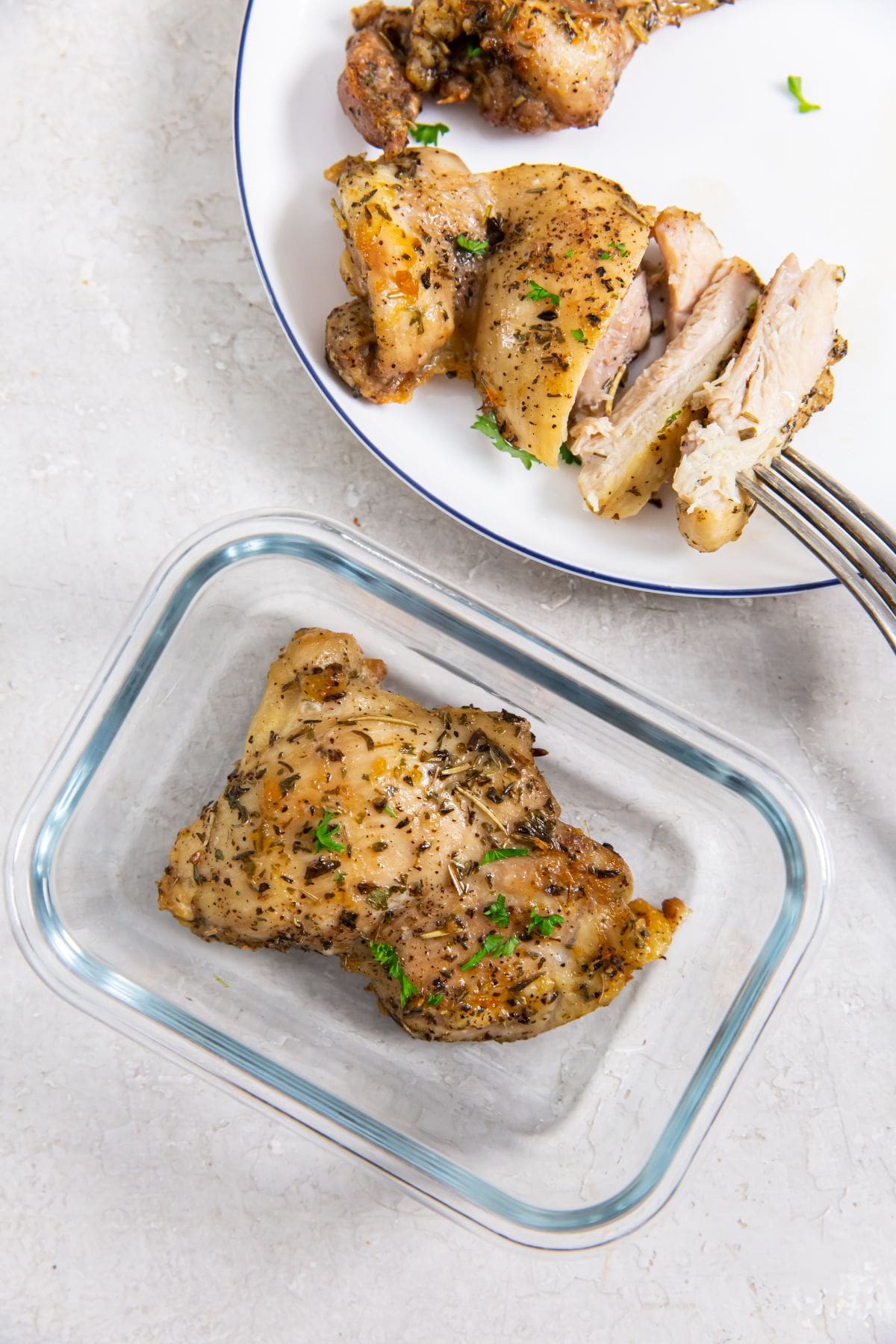 Glass storage container with chicken and plate with chicken cut up