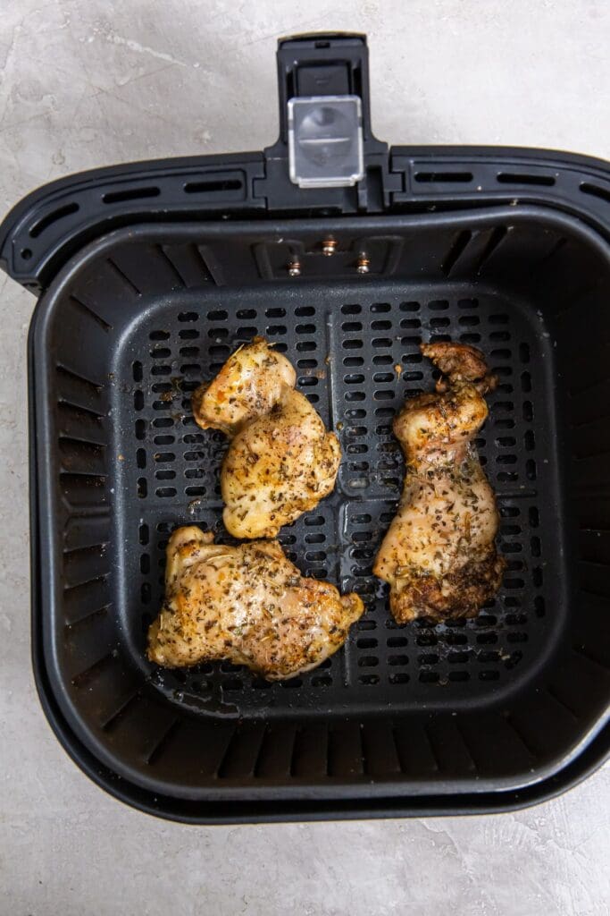 black air fryer with cooked chicken inside it