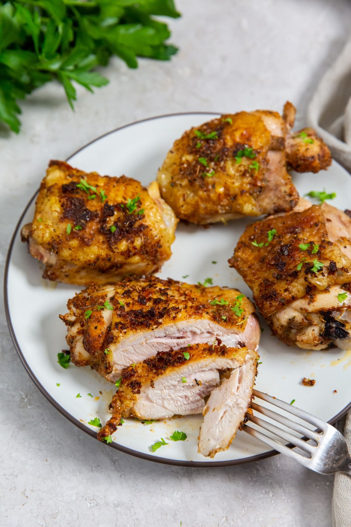 white plate with chicken on it. parsley and gray towel in the back. for on plate