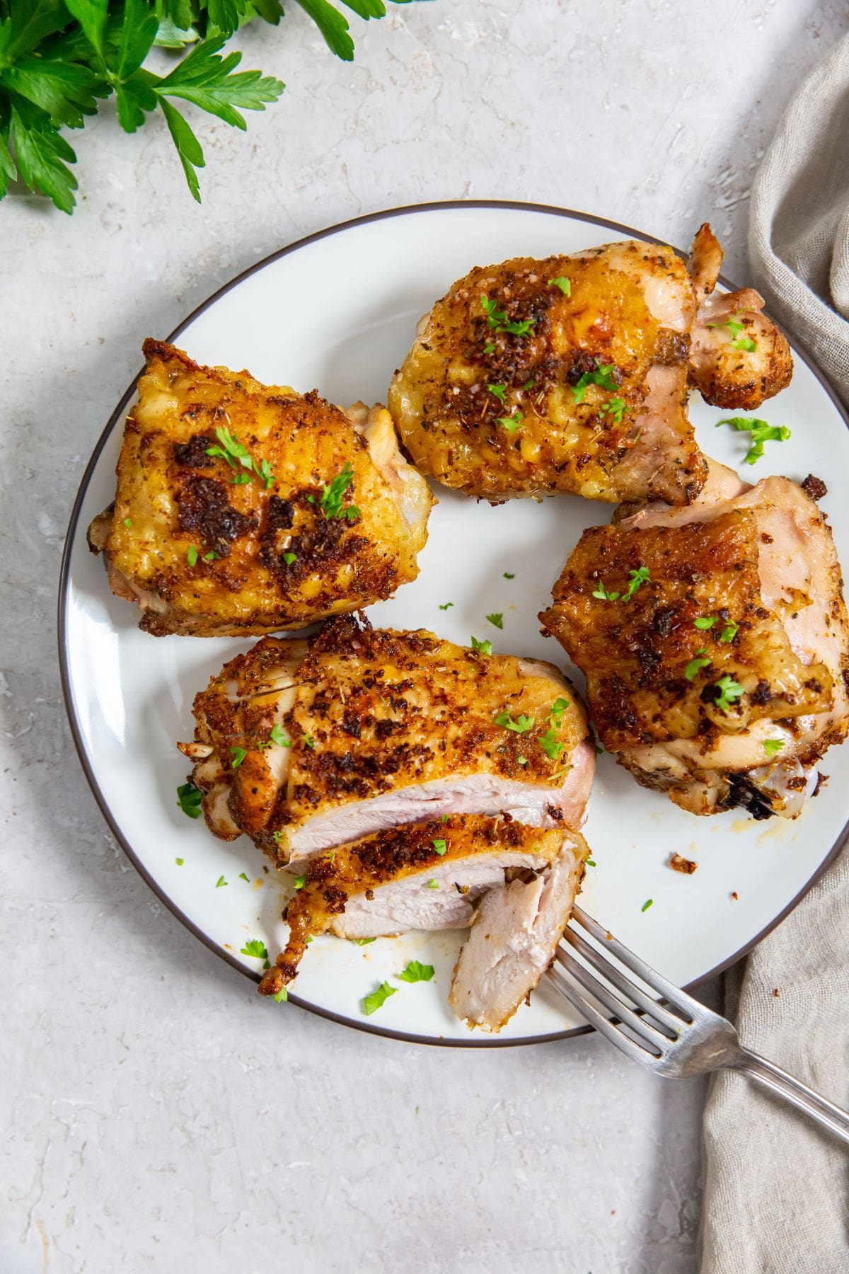 white plate with chicken on it. parsley and gray towel in the back. for on plate