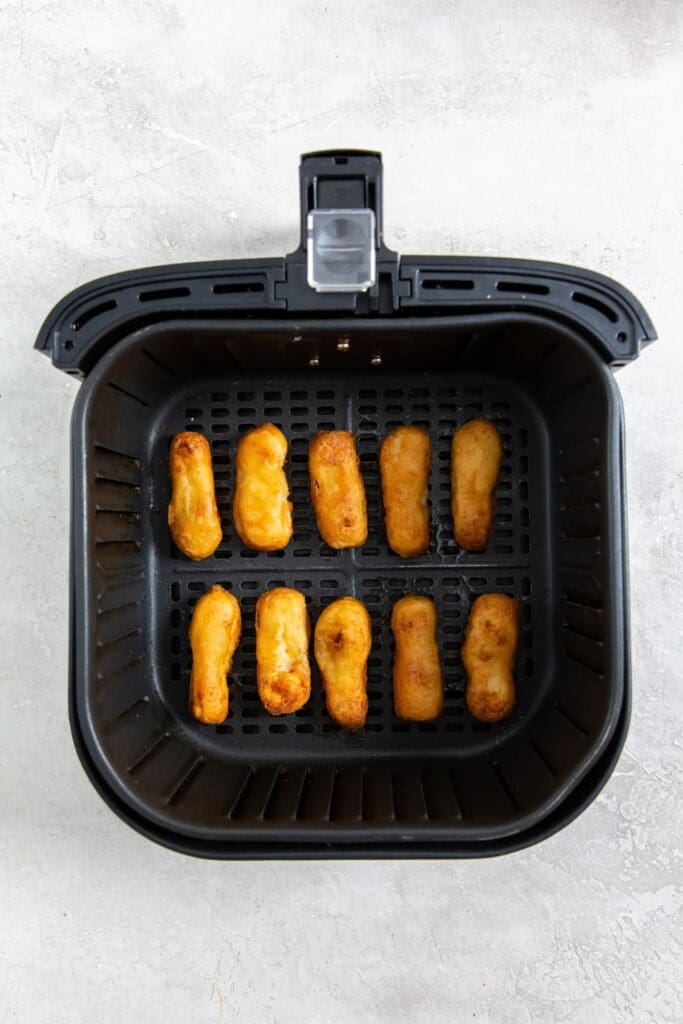 black air fryer basket with cooked chicken inside