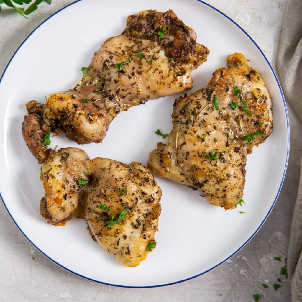 white plate with chicken on it. parsley and gray towel in the back.