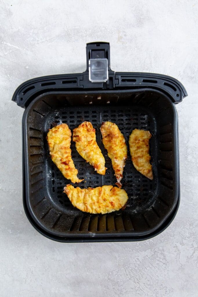 black air fryer basket with cooked chicken inside