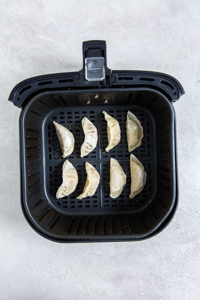 black air fryer with raw potstickers inside