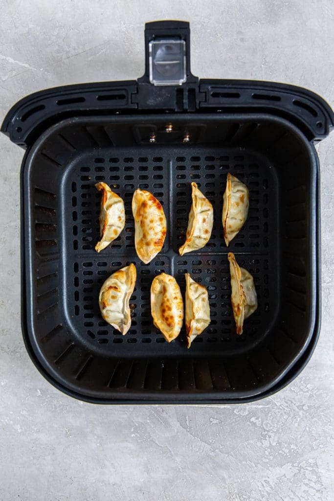 black air fryer with cooked potstickers inside