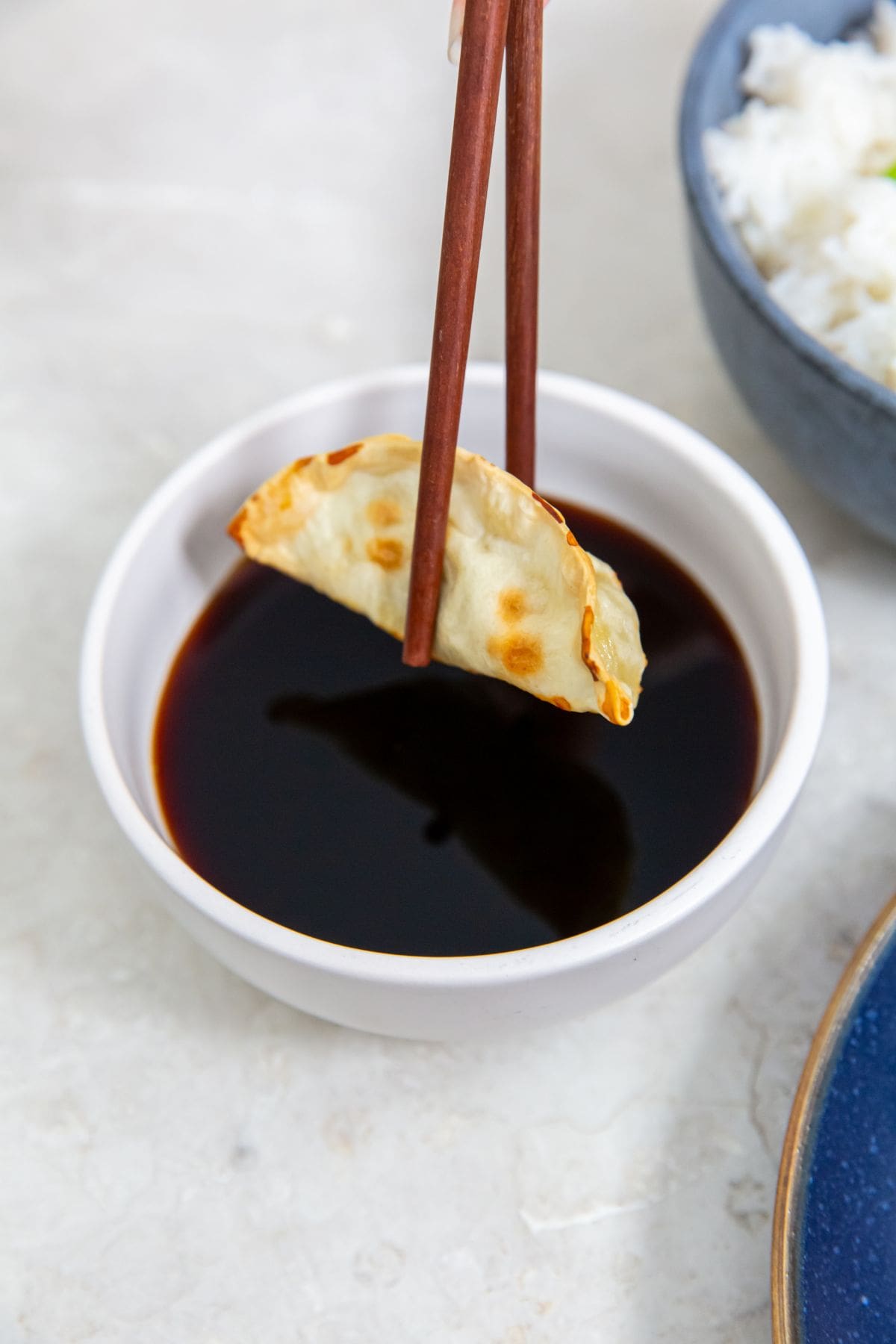 white bowl with soy sauce potsticker dipped in soy sauce