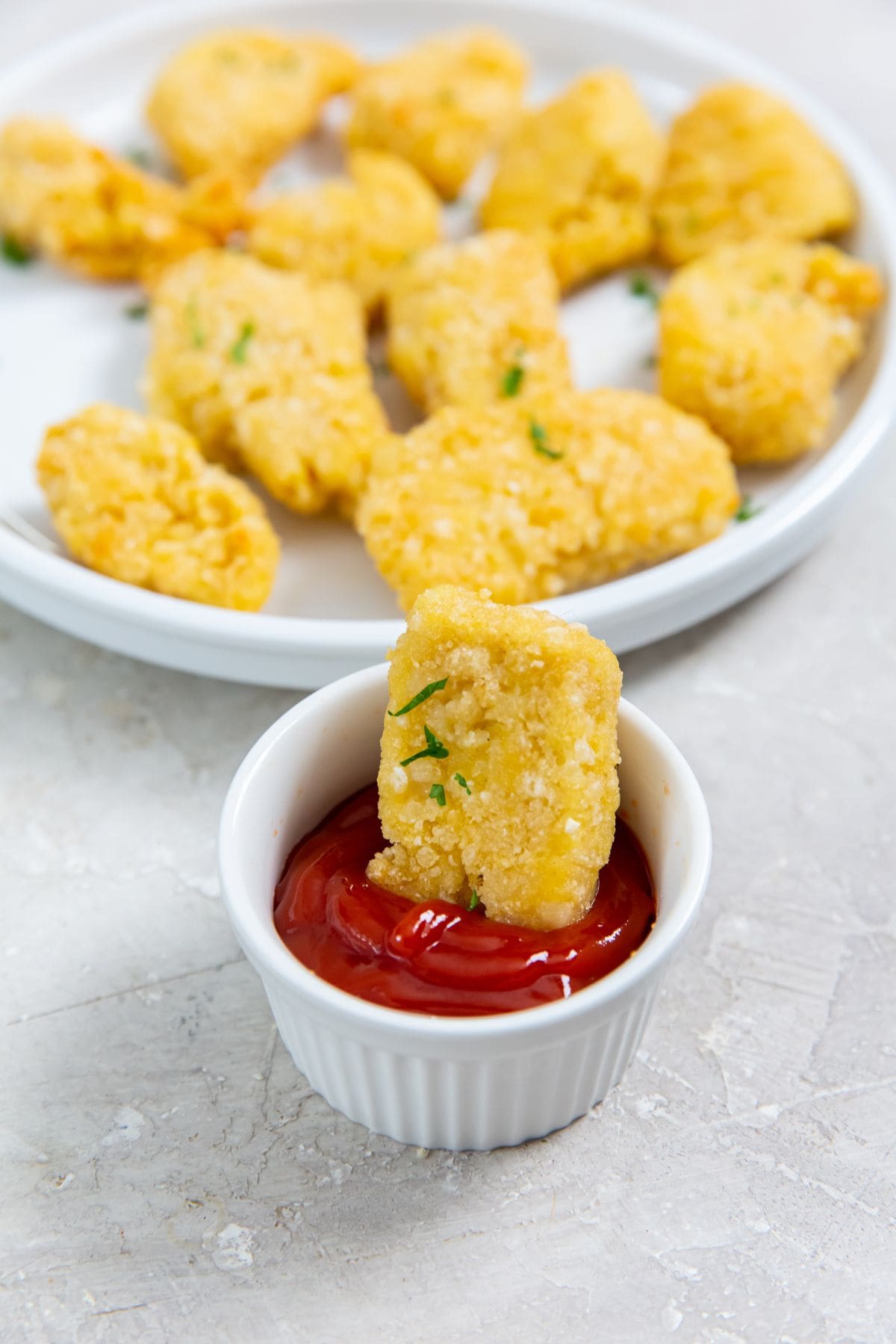 chicken dunked in a ketchup plate of nuggets next to it