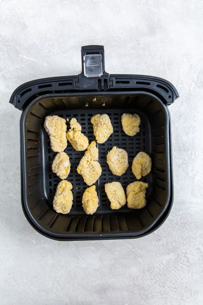 black air fryer with raw chicken inside