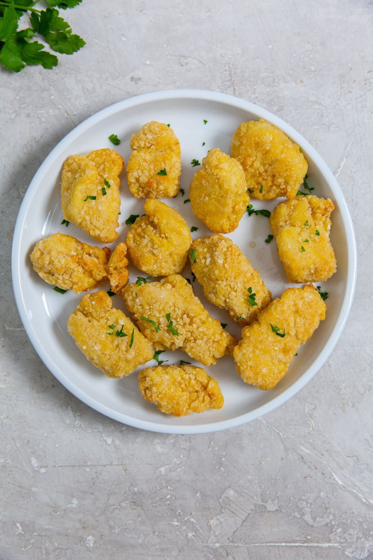 white plate with chicken on it parsley sprinkled on top