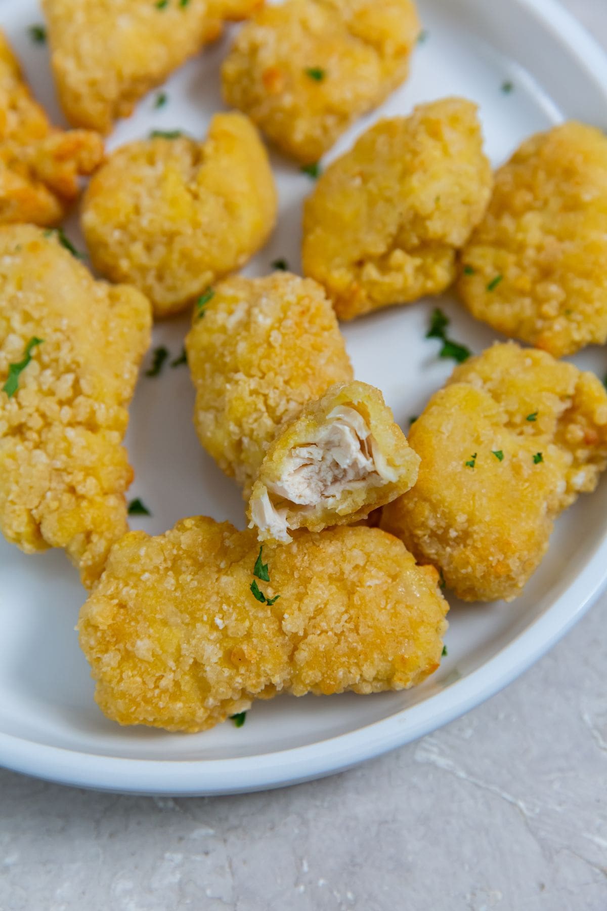 white plate with chicken on it parsley sprinkled on top