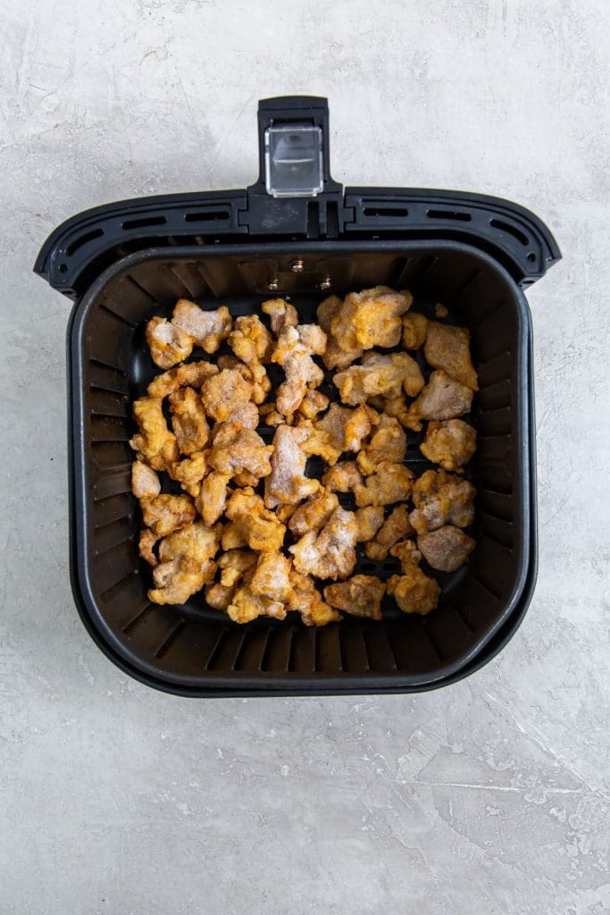 Black air fryer with frozen chicken inside