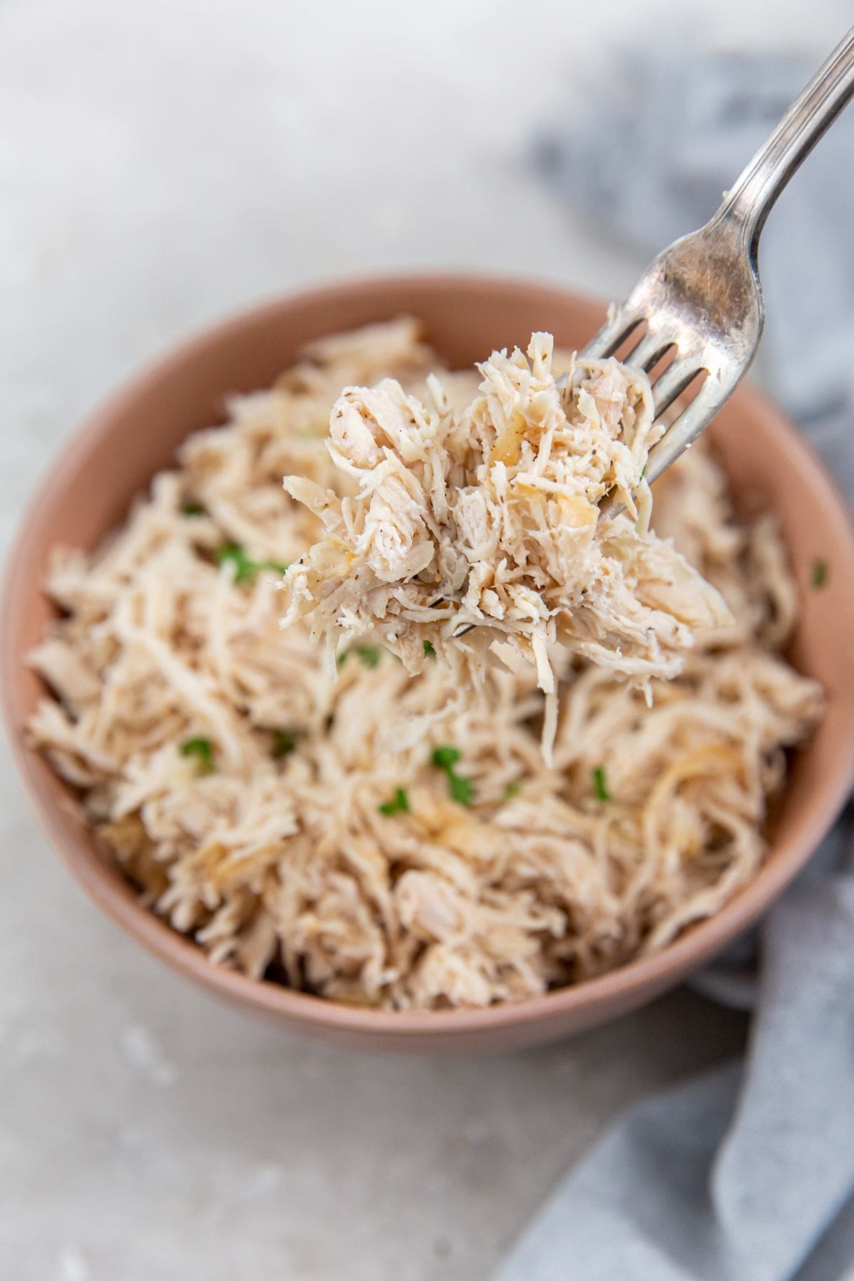 The Best Air Fryer Chicken Breast Recipes Close Up of a Fork Filled with Shredded Chicken Over a Bowl of Shredded Chicken