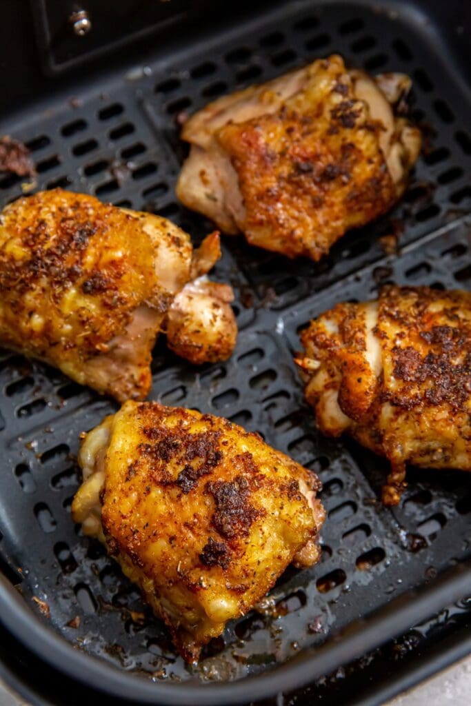 black air fryer with cooked chicken inside