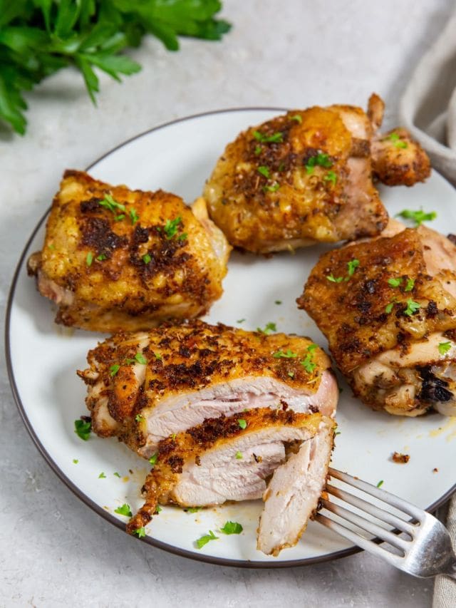 white plate with chicken on it. parsley and gray towel in the back. for on plate