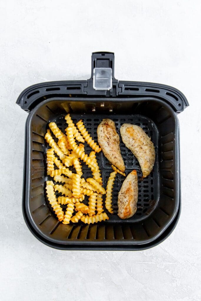 black air fryer with cooked chicken and fries inside