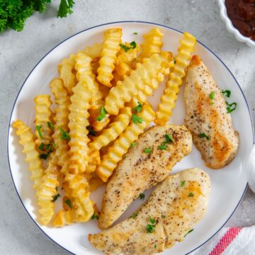 plate with chicken and fries. BBQ sauce in the back