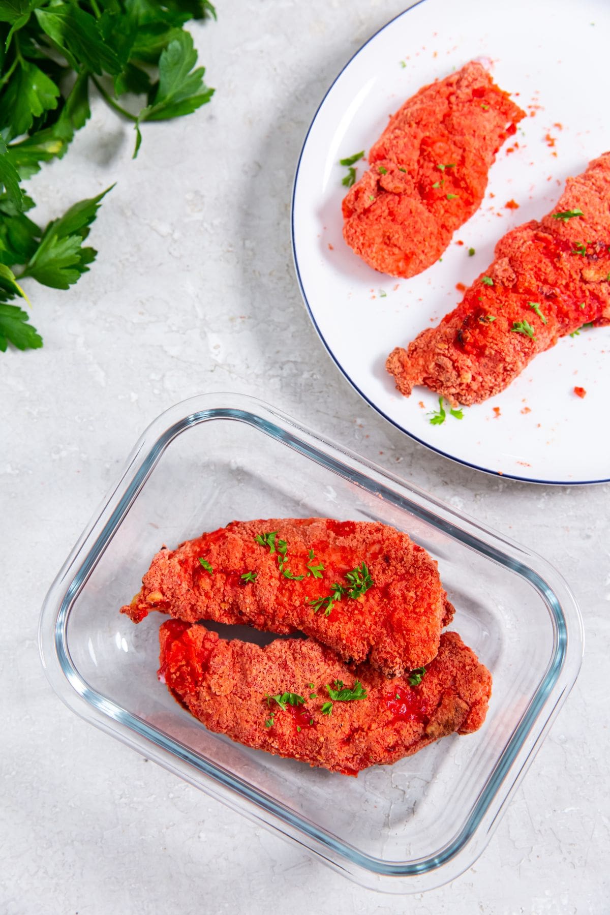 white plate with chicken. glass container with chicken inside also