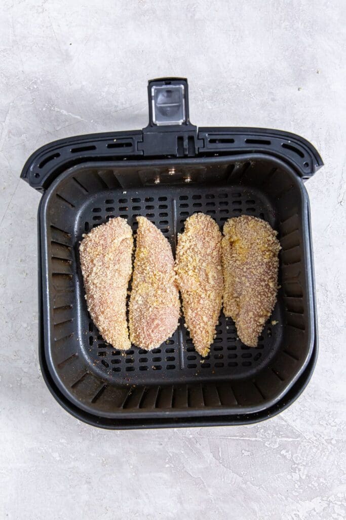 black air fryer basket with raw chicken inside