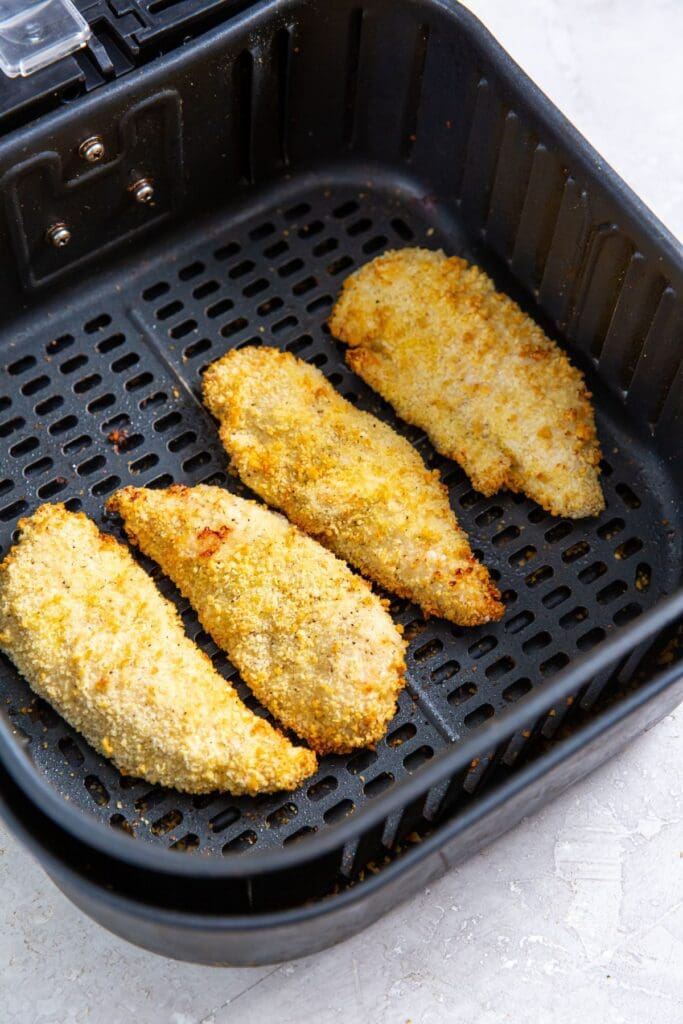 black air fryer with cooked chicken inside