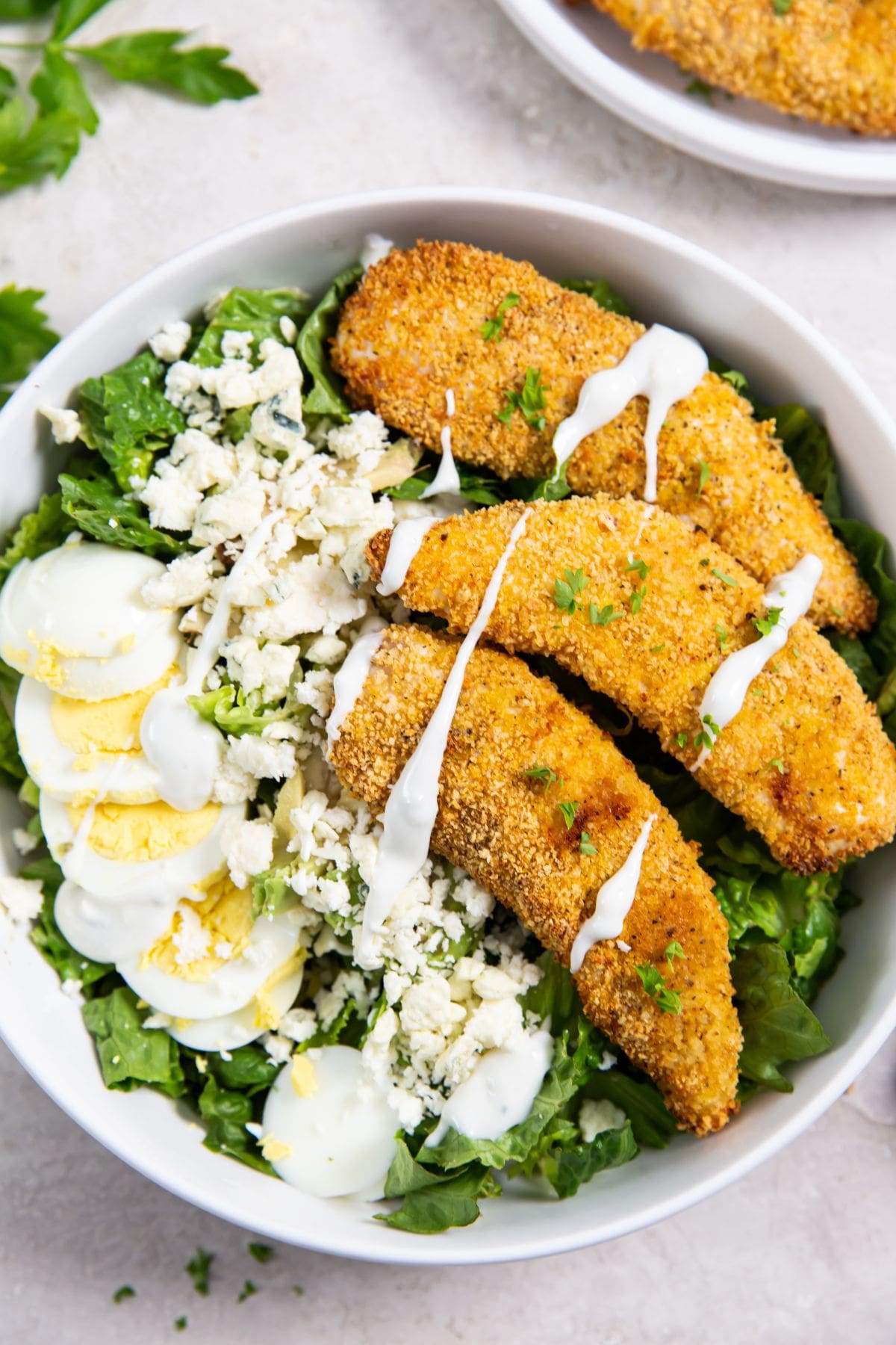 bowl with salad and chicken. chicken in the background