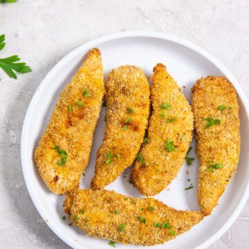 plate with chicken tenders. parsley sprinkled on top and in the back