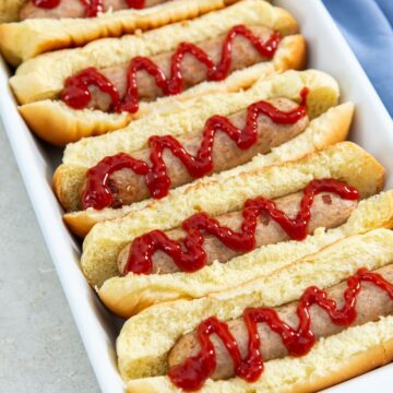 chicken sausage in buns with ketchup on it. blue towel next to it