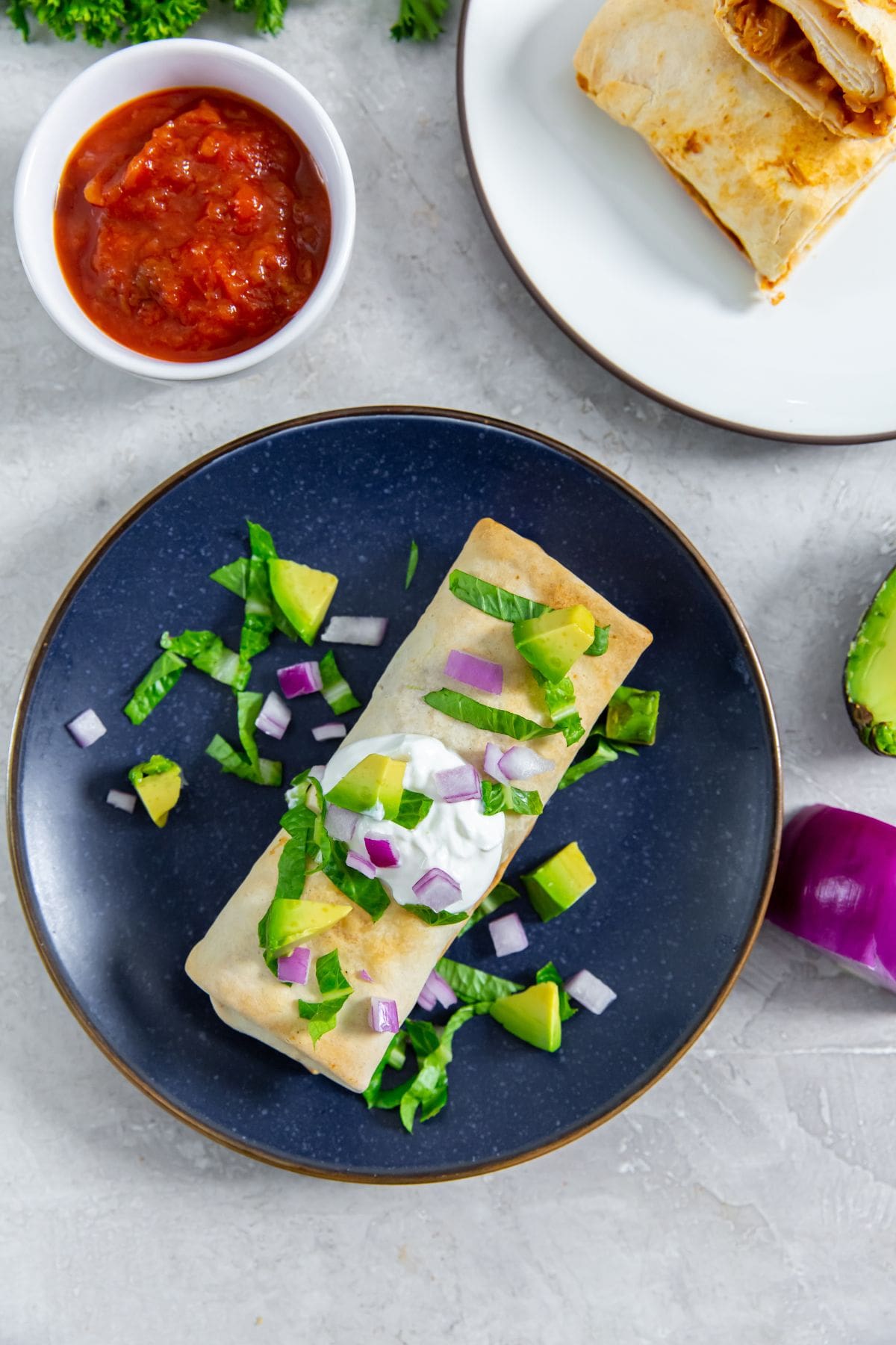 burrito with sour cream avocado and lettuce salsa in the back