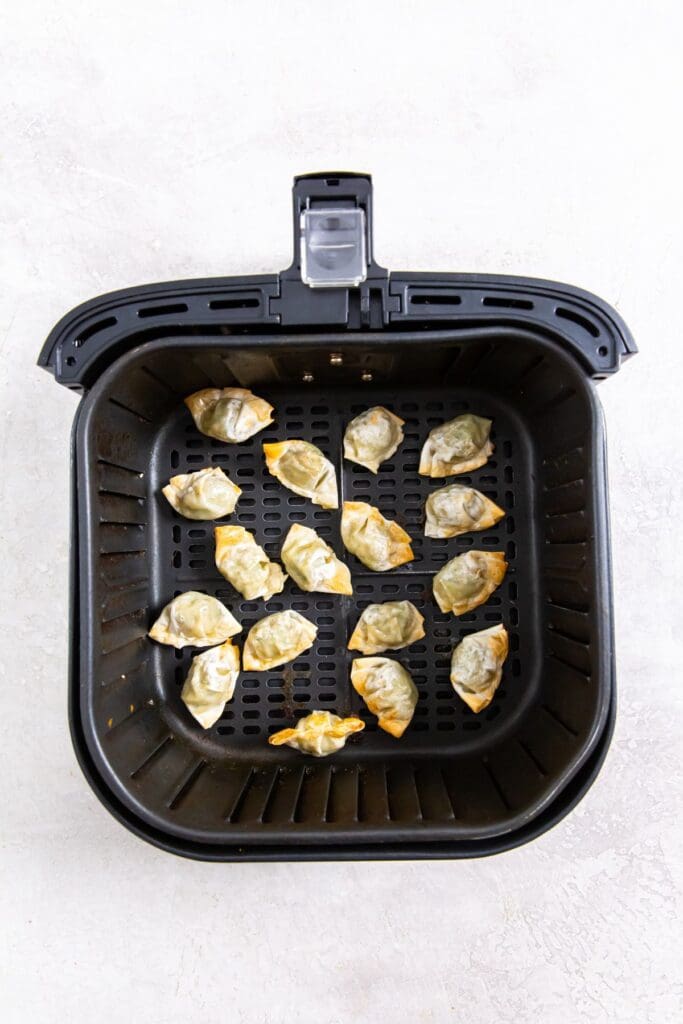 black air fryer basket with wontons inside