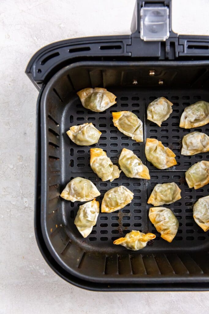 black air fryer basket with wontons inside