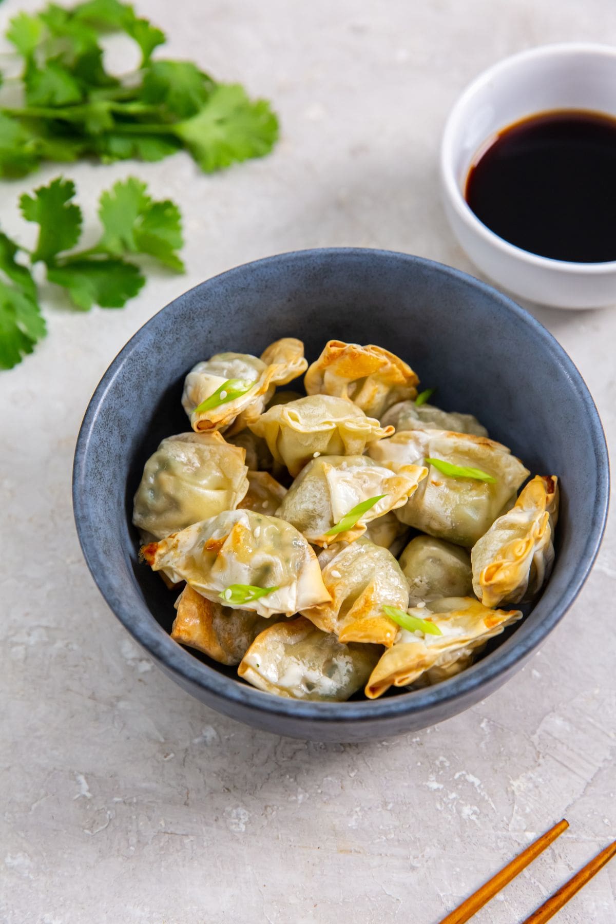 Air Fryer Chicken Cilantro Mini Wontons in a blue bowl with cilantro in the background