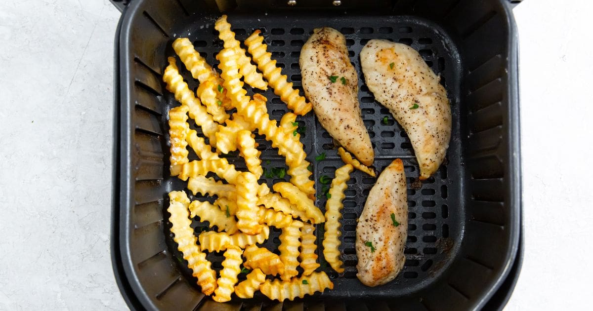 black air fryer with cooked chicken and fries inside