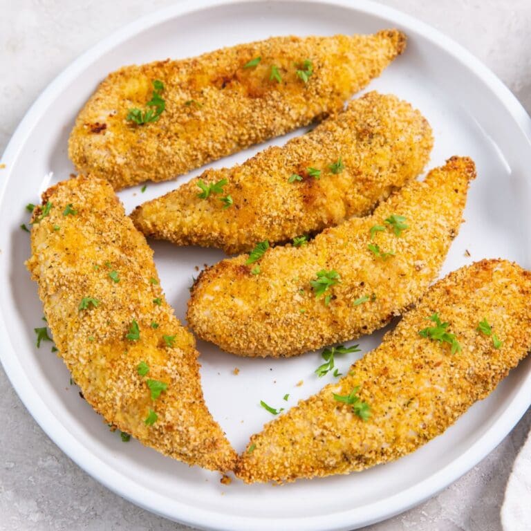 plate with chicken tenders. parsley sprinkled on top and in the back