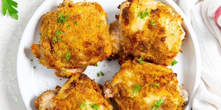 white plate with chicken on it. parsley in the back. white towel next to it