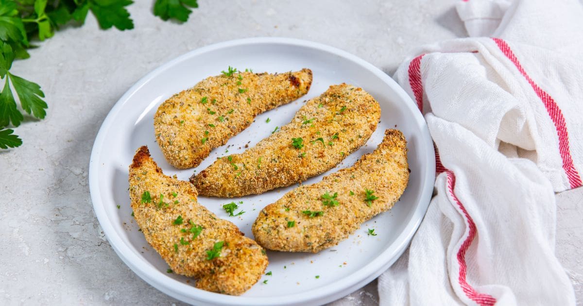 white plate with chicken on it. parsley and white and pink towel in the back