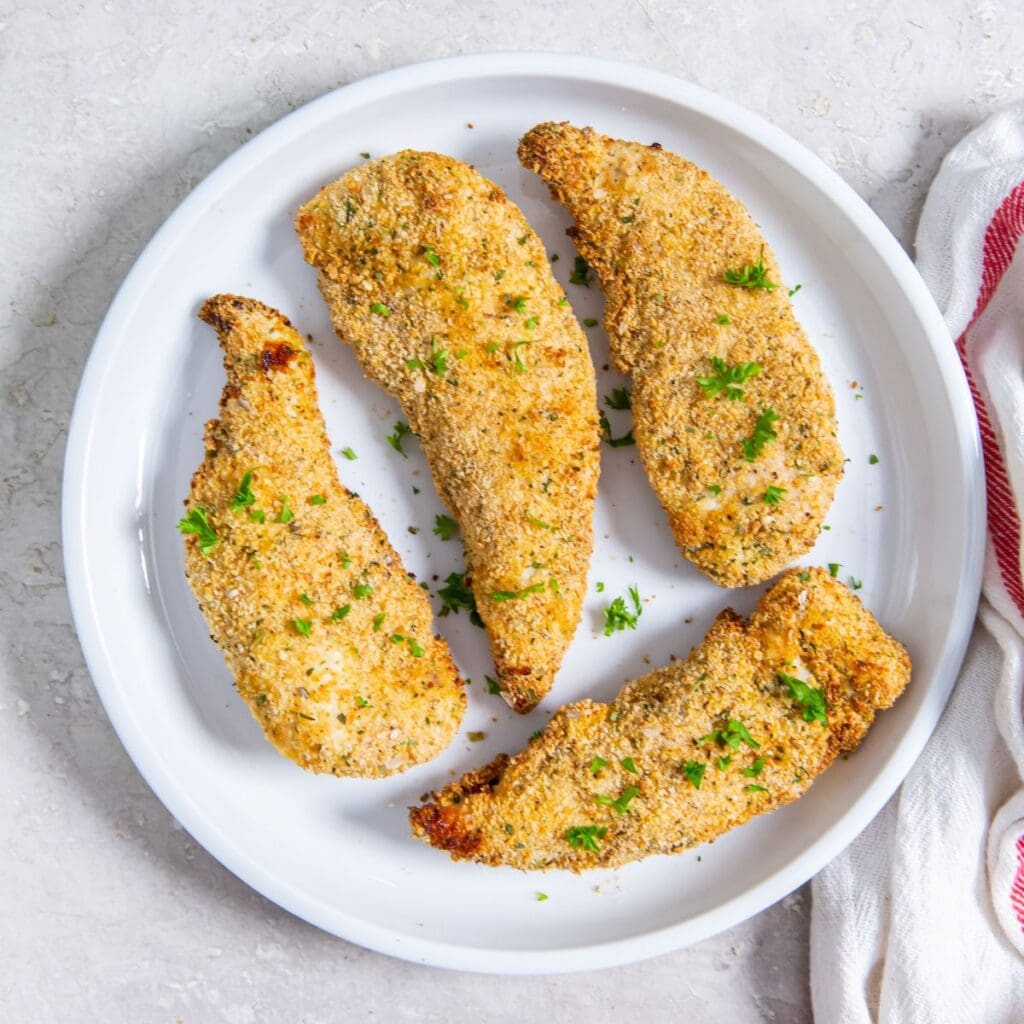 white plate with chicken on it. white towel next to it