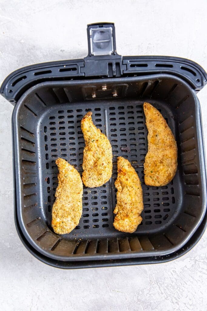 black air fryer basket with cooked chicken inside