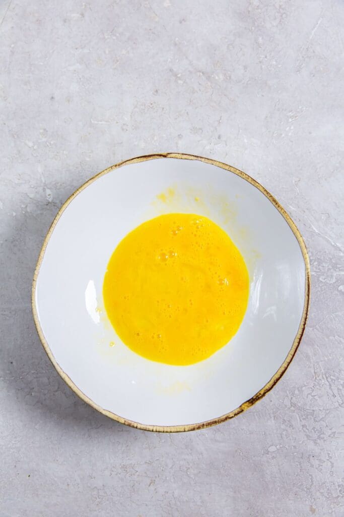 white bowl with egg whisked together