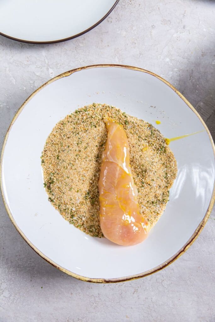 white bowl with chicken sitting in bread crumbs