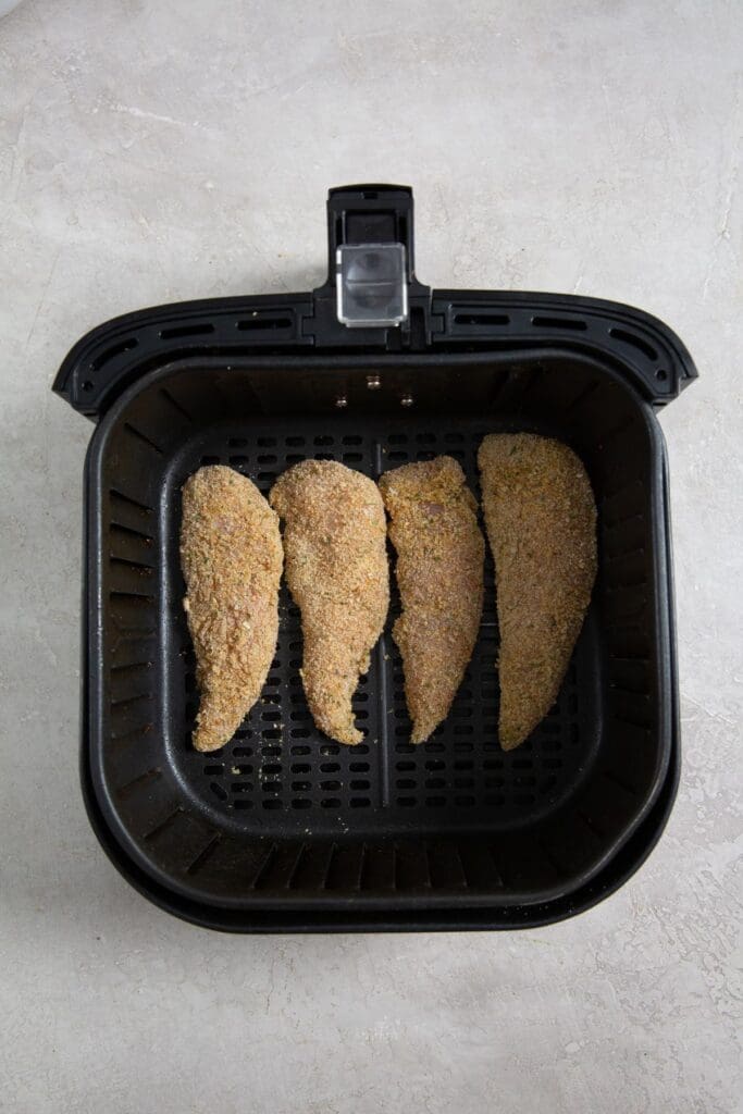 black air fryer basket with raw chicken inside