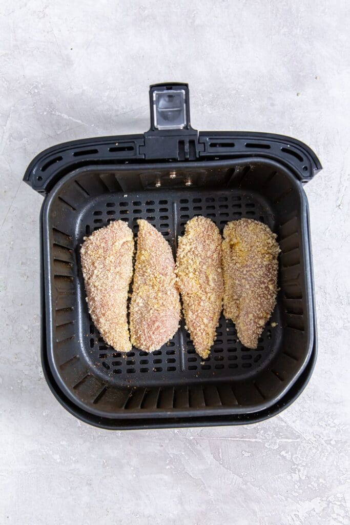 black air fryer basket with raw chicken inside