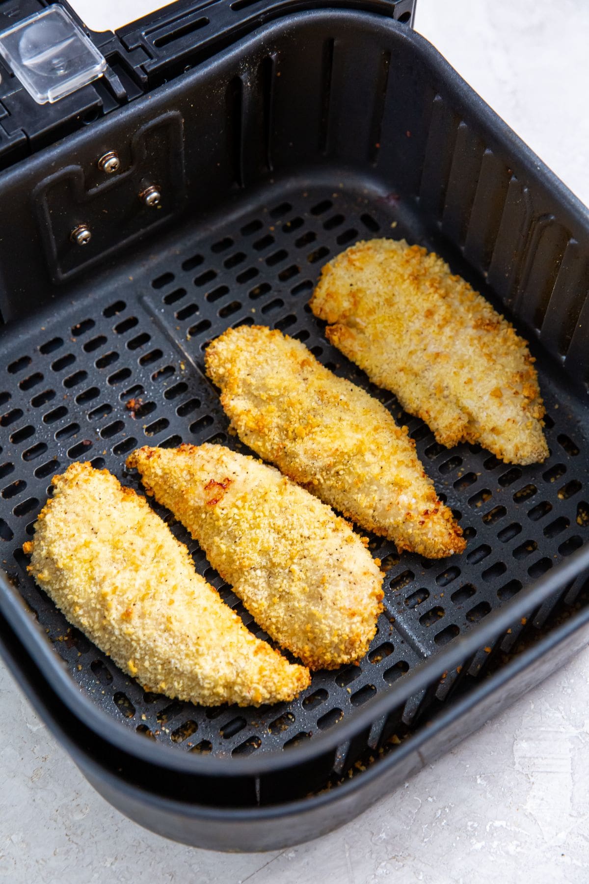 black air fryer basket with cooked chicken inside