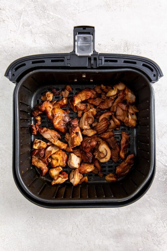 black air fryer with cooked chicken inside