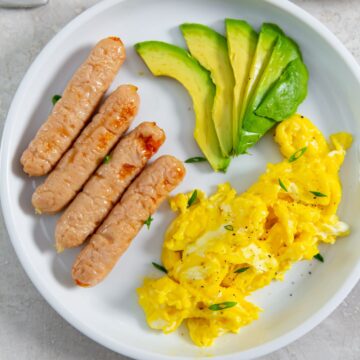 plate with sausage, eggs, and avocado slices.